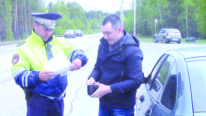 Инспектор ГИБДД Николай Снедков проверяет у водителя документы